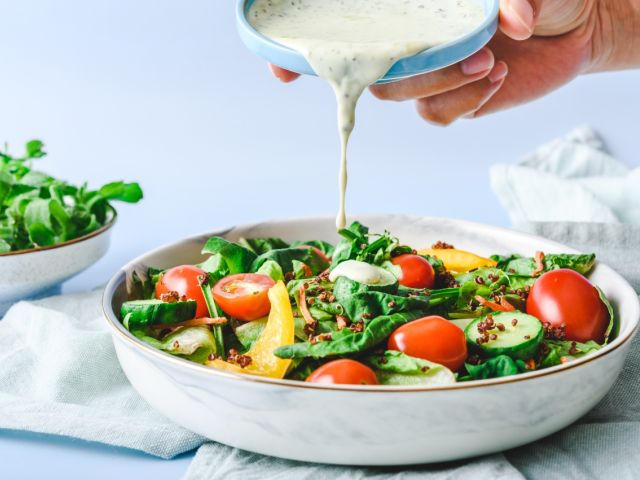 Dressing being poured over a salad